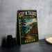 A vintage-style metal sign for Guy W. Talbot State Park, featuring a scenic landscape with pine trees, a beach, and mountains in the background.