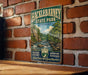 A vintage-style metal sign for Hackleton Pond State Park in New Jersey, featuring a scenic illustration of a river and forest landscape.