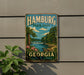 A vintage-style metal sign for Hamburg State Park in Georgia, featuring a scenic landscape with a river, trees, and a waterfall.