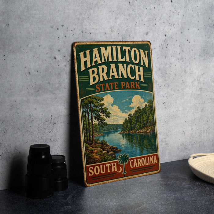 A vintage-style metal sign for Hamilton Branch State Park in South Carolina, featuring a scenic landscape with a lake and trees.