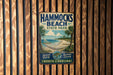 A vintage metal sign for Hammocks Beach State Park in North Carolina, featuring a beach scene with palm trees and a hammock.