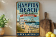 A vintage-style sign for Hampton Beach State Park in New Hampshire, featuring a beach scene with a lifeguard chair, a ferris wheel, and a sign that says "Sun, Sand & Seaside Fun!"