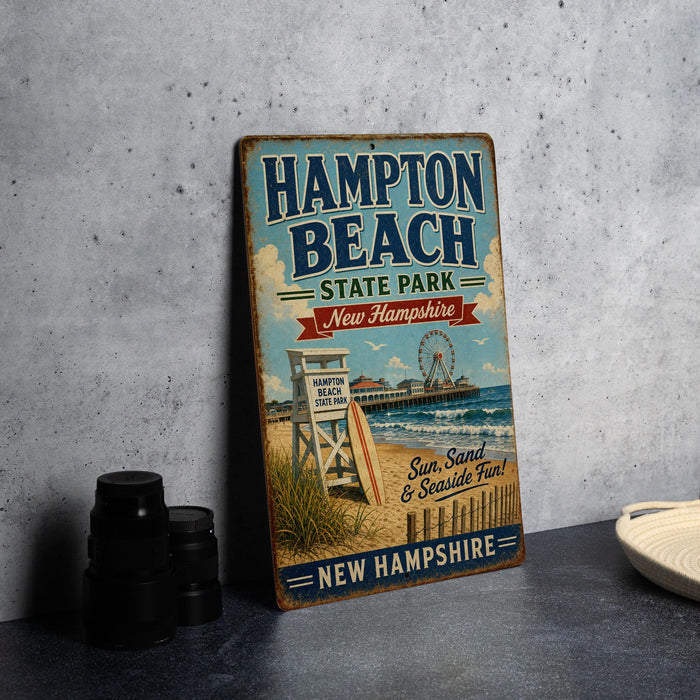 A vintage-style sign for Hampton Beach State Park in New Hampshire, featuring a beach scene with a lifeguard chair, a ferris wheel, and a sign that says "Hampton Beach, New Hampshire".