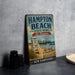 A vintage-style sign for Hampton Beach State Park in New Hampshire, featuring a beach scene with a lifeguard chair, a ferris wheel, and a sign that says "Hampton Beach, New Hampshire".