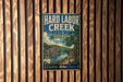 A vintage-style metal sign for Hard Labor Creek State Park in Georgia, featuring a scenic landscape with a river, mountains, and a cabin.