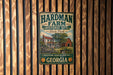 A vintage metal sign for the Hardman Farm Historic Site in Georgia, featuring a farm scene with a barn and a tree.