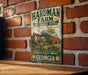 A vintage metal sign for the Hardman Farm Historic Site in Georgia, featuring an illustration of a farm scene with a barn and a horse.
