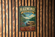 A vintage metal sign for the Harmonie State Park in Indiana, featuring a scenic landscape with a river, trees, and a rock formation.