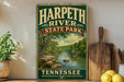 A vintage-style sign for Harpeth River State Park in Tennessee, featuring a scenic illustration of the river surrounded by lush greenery.