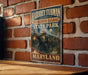 A vintage-style metal sign for Harriet Tubman's Underground Railroad State Park in Maryland, featuring an illustration of a person holding a lantern and a wagon.