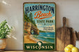 A vintage-style sign for Harrington Beach State Park in Wisconsin, featuring a scenic beach landscape with a rock formation and ocean.
