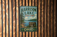 A vintage metal sign for Harrison Lake State Park in Ohio, featuring a scenic landscape with a lake and mountains.