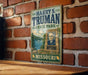 A vintage metal sign for "Harry S. Truman State Park" in Missouri, featuring a portrait of a man and a scenic landscape.