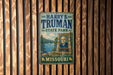 A vintage metal sign for "Harry S. Truman State Park" in Missouri, featuring a portrait of a man and a scenic landscape.