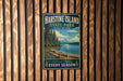 A vintage-style metal sign for Harstine Island State Park in Washington, featuring a scenic landscape with a mountain, lake, and pine trees.