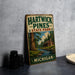 A vintage-style metal sign for Hartwick Pines State Park in Michigan, featuring a scenic illustration of a cabin and a river surrounded by pine trees.