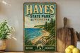 A vintage-style poster of Hayes State Park, Michigan, featuring a scenic coastal landscape with a wooden staircase leading to a cliff overlooking the ocean.