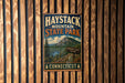 A vintage metal sign for Haystack Mountain State Park in Connecticut, featuring a scenic mountain landscape and trail information.