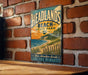A vintage-style metal sign for Headlands Beach State Park in Gold, featuring a scenic beach landscape with a lighthouse and a wooden fence.