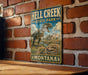 A vintage-style metal sign for Hell Creek State Park in Montana, featuring a dinosaur illustration and the park's name.
