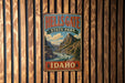 A vintage metal sign for Hells Gate State Park in Idaho, featuring a scenic mountain landscape.