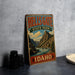 A vintage metal sign for Hells Gate State Park in Idaho, featuring a scenic mountain landscape.