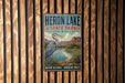 A vintage-style sign for Heron Lake State Park in New Mexico, featuring a heron in a grassy landscape with mountains in the background.