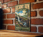 A vintage-style metal sign for Hickory Run State Park in Pennsylvania, featuring a scenic landscape with a waterfall and pine trees.
