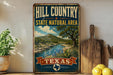 A vintage-style sign for the Hill Country State Natural Area in Texas, featuring a scenic landscape with a river, mountains, and various flora.