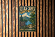 A vintage metal sign for Hills Creek State Park in Pennsylvania, featuring a scenic landscape with a lake, mountains, and a picnic area.