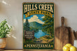 A vintage-style sign for Hills Creek State Park in Pennsylvania, featuring a scenic landscape with a river, mountains, and a picnic area.