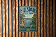 A vintage metal sign for Hillsdale State Park in Kansas, featuring a scenic landscape with a lake and mountains.