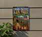 A vintage-style metal sign for the Union Pacific Rail Trail in Utah, featuring a scenic image of a bridge and mountains.