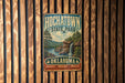 A vintage-style metal sign for HochatOWN State Park in Oklahoma, featuring a scenic landscape with a waterfall and pine trees.