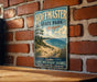 A vintage metal sign for Hoffman State Park, Michigan, featuring a scenic beach landscape with a pine tree and a lake.