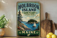 A vintage-style sign for Holbrook Island, Maine, featuring a scenic illustration of a sailboat on the water and a forested island in the background.