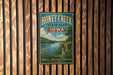 A vintage-style sign for Honey Creek State Park in Iowa, featuring a scenic landscape with a river, cliffs, and wildflowers.