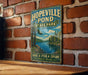 A vintage-style metal sign for Hopeville Pond State Park in Connecticut, featuring a scenic landscape with a lake, trees, and mountains.