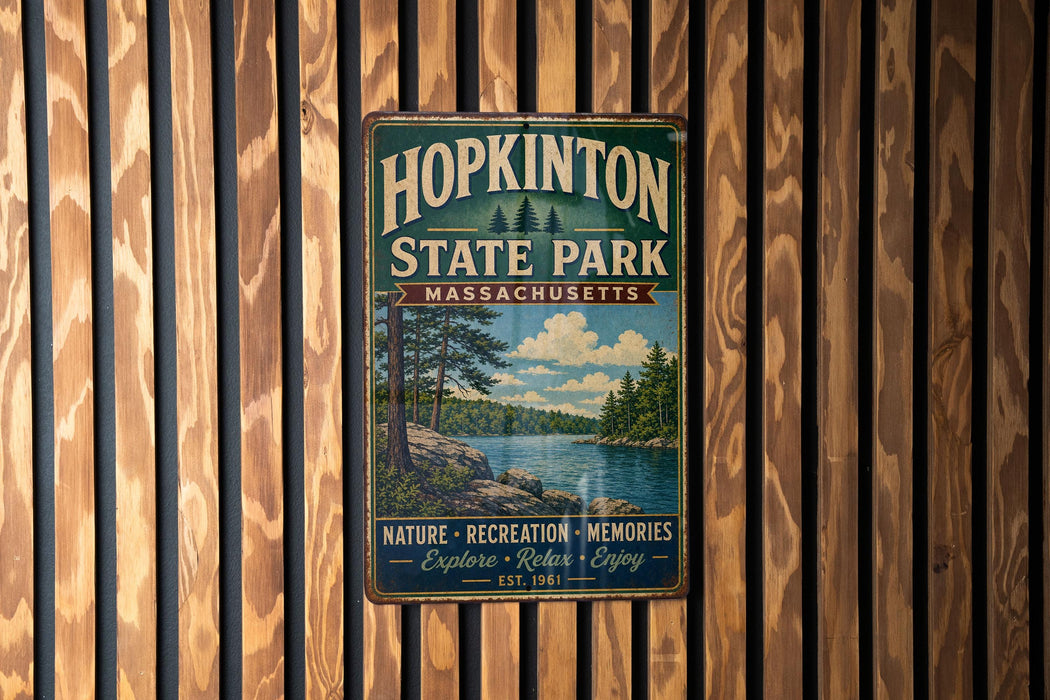 A vintage metal sign for Hopkinton State Park in Massachusetts, featuring a scenic landscape with a lake and pine trees.