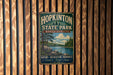 A vintage metal sign for Hopkinton State Park in Massachusetts, featuring a scenic landscape with a lake and pine trees.