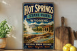 A vintage-style sign for Hot Springs State Park in Wyoming, featuring a scenic illustration of the natural hot springs and mountains.