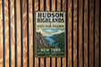 A vintage-style metal sign for Hudson Highlands State Park Preserve, featuring a scenic landscape with mountains, a river, and a boat.