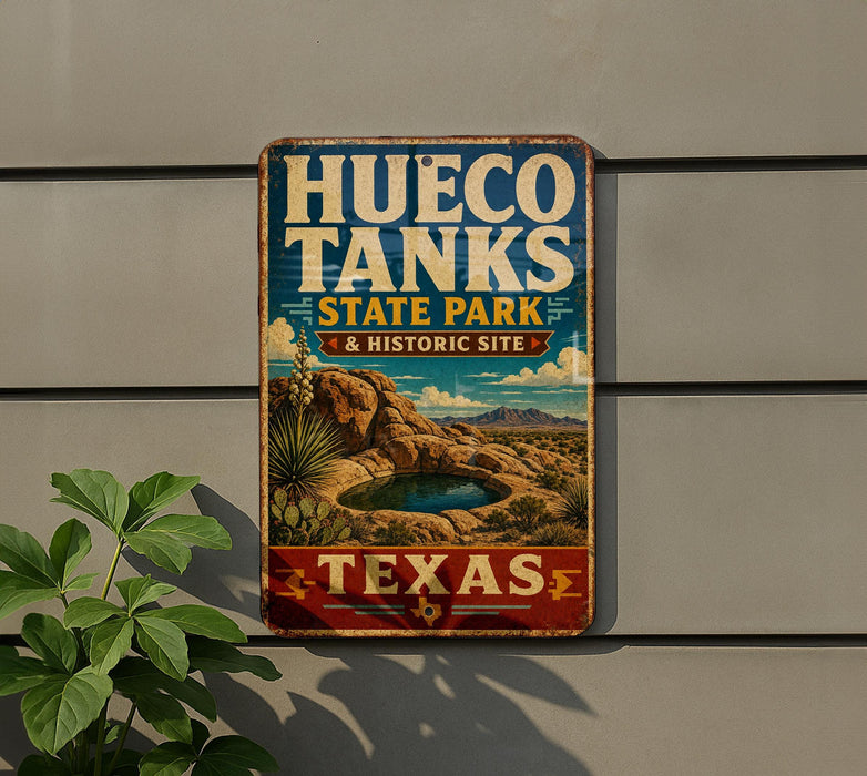 A vintage-style metal sign for Hueco Tanks State Park & Historic Site in Texas, featuring a desert landscape with a small lake and mountains in the background.