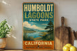 A vintage-style sign for Humboldt Lagoon State Park in California, featuring a scenic landscape with a lake and mountains.