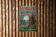 A vintage metal sign for Humboldt Redwoods State Park in California, featuring a scenic illustration of the park's iconic redwood trees.
