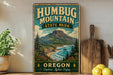 A vintage-style metal sign for Humbug Mountain State Park in Oregon, featuring a scenic mountain landscape with pine trees, a lake, and a beach.