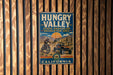A vintage metal sign for the Hungry Valley State Vehicular Recreation Area in California, featuring an illustration of off-road vehicles and a scenic mountain landscape.