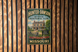 A vintage metal sign for the Hunter-Dawson State Historic Site in Missouri, featuring an illustration of a historic house surrounded by trees.