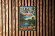 A vintage-style metal sign for the "Piney Woods Adventure" at the "Huntsville State Park, Texas" is displayed on a wooden wall.
