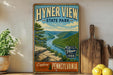 A vintage-style metal sign for Hyner View State Park in Pennsylvania, featuring a scenic mountain landscape with a winding river.